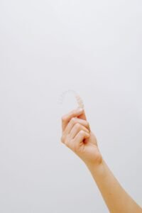 Hand holding a clear orthodontic retainer used after braces or Invisalign
