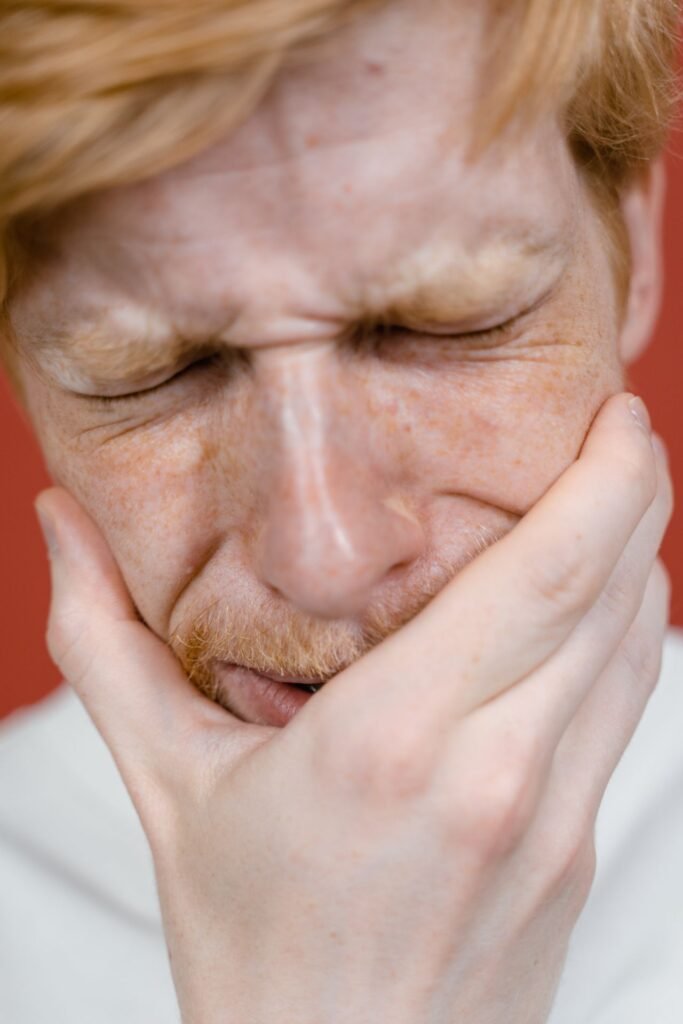 Man with eyes closed feeling tooth pain from sweets in Woodbridge