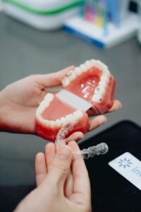 Hands holding clear aligners next to a dental model